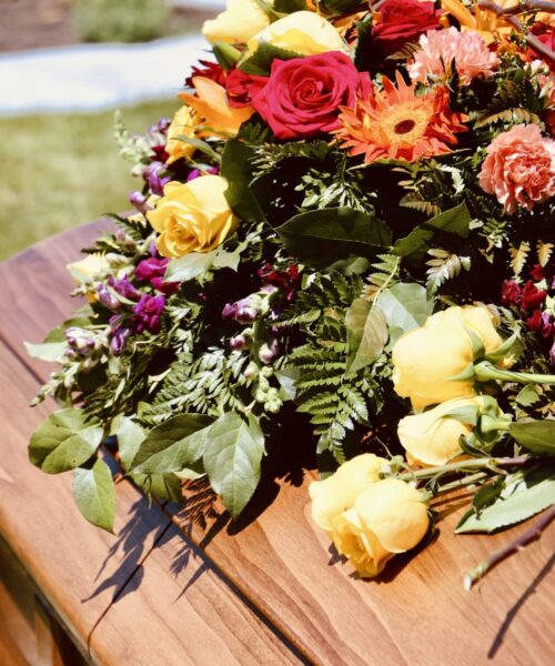 Lovely floral arrangement on wood casket.